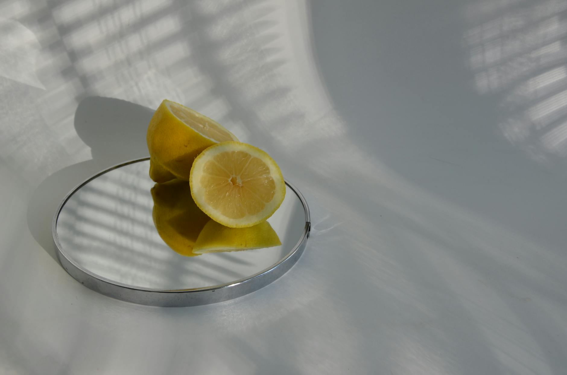Limões fatiados em espelho criando sombras minimalistas