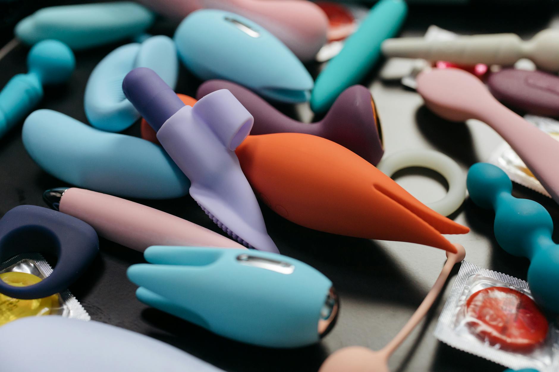 Close-up array of colorful vibrators and intimate wellness toys on a neutral surface