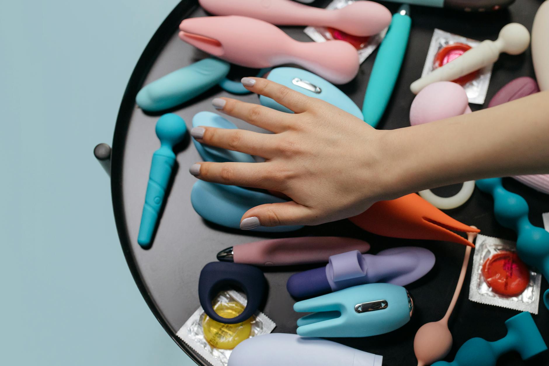 Vibrador rosa em fundo roxo com confetes em forma de coração e velas para clima romântico